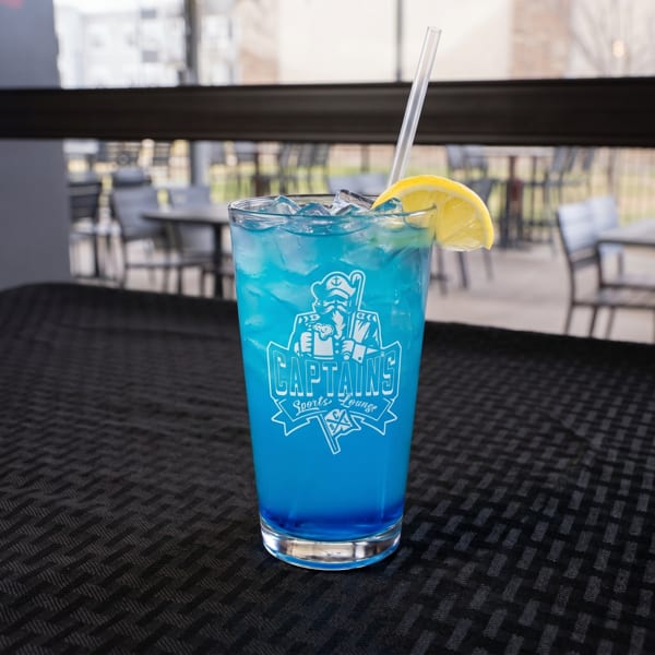 Blue cocktail with ice, a lemon slice, and a straw, featuring the "Captain's Sports Lounge" logo.